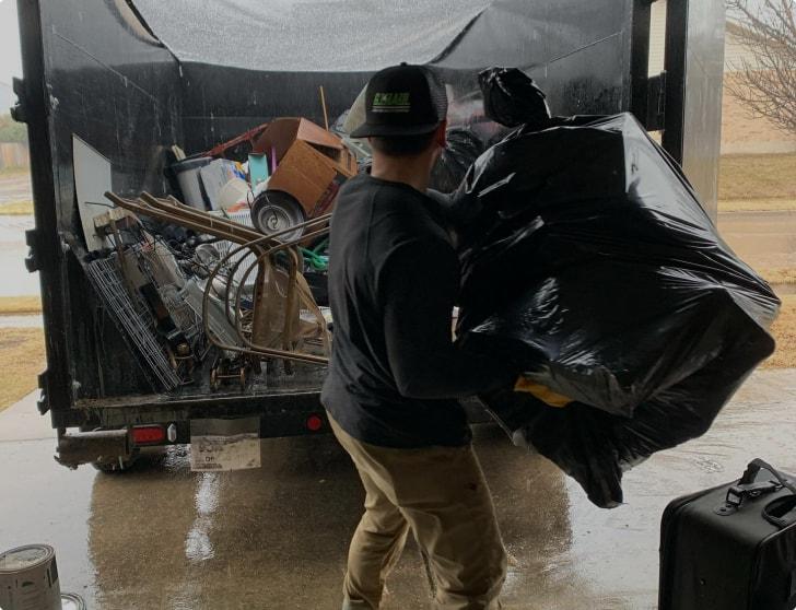gentleman throwing bag of trash in the back of truck